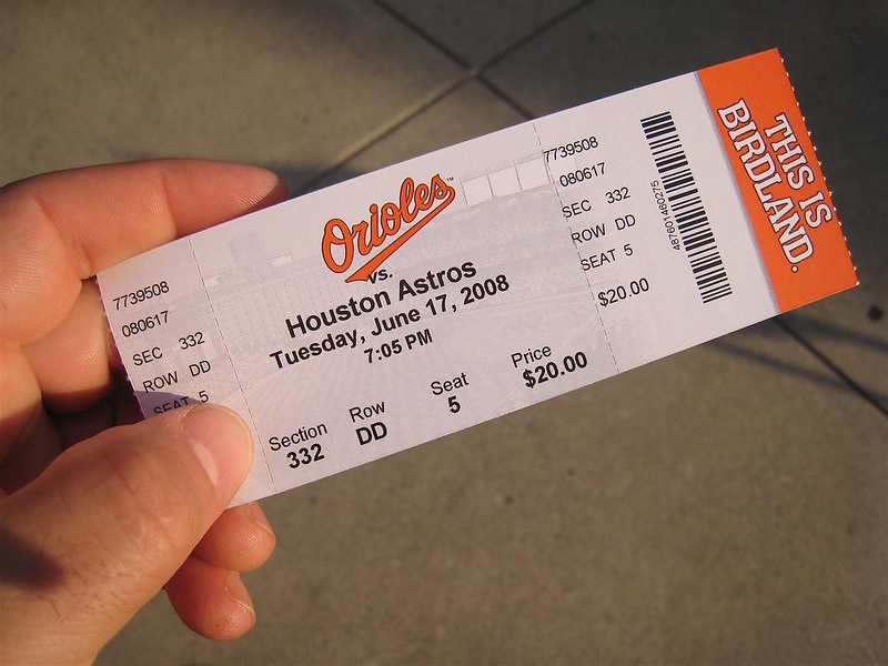 Photo of a baseball fan holding a ticket to a Baltimore Orioles game at Oriole Park at Camden Yards.