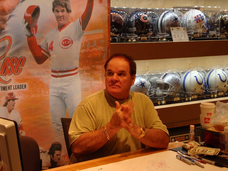 Photo of Pete Rose signing autographs at a public event.