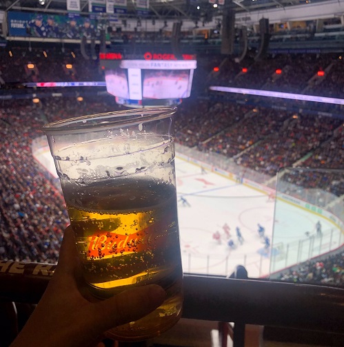 Photo of a fan holding a beer while watching a Vancouver Canucks game at Rogers Arena.