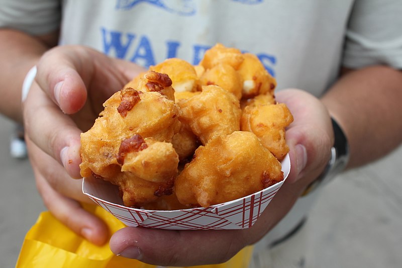 Photo of a baseball fan holding cheese curds.