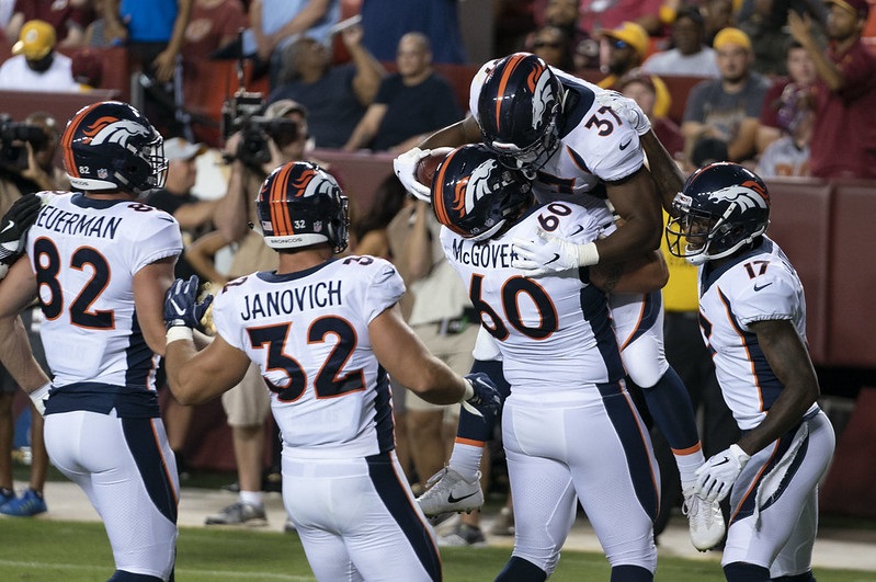Photo of Denver Broncos players celebrating a touchdown in the end zone. 