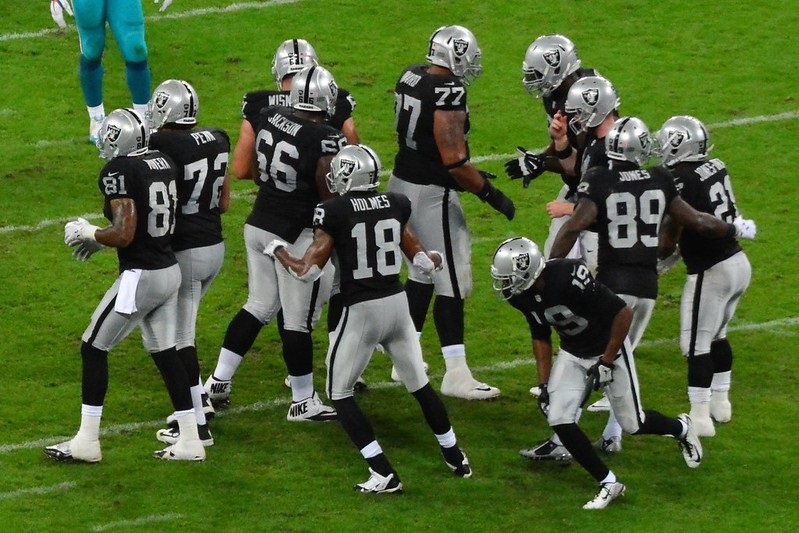 Photo of Oakland Raiders players in the huddle during a game versus the Miami Dolphins.