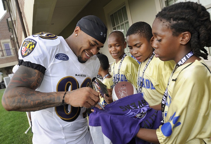 Photo of NFL wide receiver Steve Smith signing autographs for young fans.