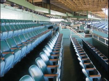 Stock photo of empty seats under a canopy at an outdoor stadium.